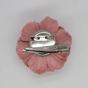Macro detail of pink fabric flower accessory with functional metal pin and hair clip back