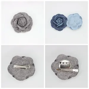 Detail von Kamelien-Stoffnadeln aus grauem Filz und Denim mit Haarclip und Brosche