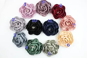 Flat lay of handmade fabric camellia pins in 11 colors with pearl centers on white background