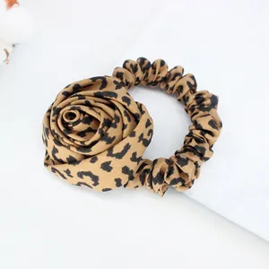 Detail of leopard print scrunchie featuring a 3D fabric rose and chiffon texture