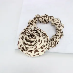 Vintage leopard print rose hair scrunchie with large fabric flower on marble background
