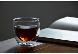Vista dettagliata di una tazza da tè in vetro isolata a doppia parete su un elegante tappeto in bambù