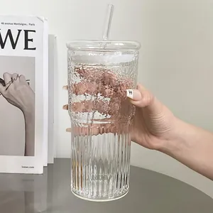 Detail view of large glass cup with hammer texture and vertical stripes held by hand