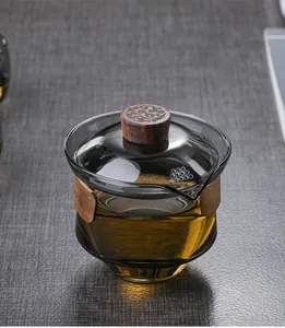 Macro shot of heat-resistant glass tea gaiwan featuring a carved wooden thermal handle