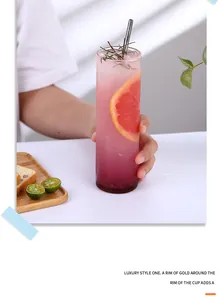Détail d'un grand verre Collins avec bord doré, cocktail, pamplemousse et paille en métal