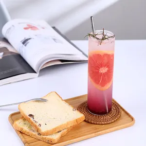 Verre Collins japonais avec cocktail rose et paille en métal sur plateau en bois