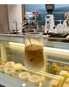 Dettaglio del bicchiere a coste con latte macchiato ghiacciato e cucchiaio in acciaio