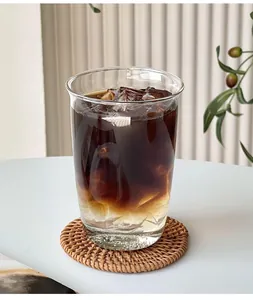 Tasse à café en verre transparent sur sous-verre en rotin tressé au style scandinave