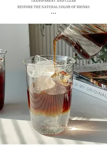Vue macro d'un verre thermorésistant transparent avec glaçons et versement de café