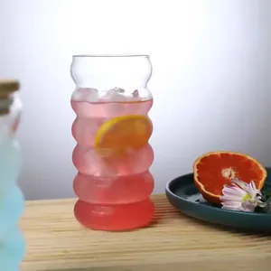 Detail of a wavy caterpillar glass cup filled with a pink cold drink and orange slices