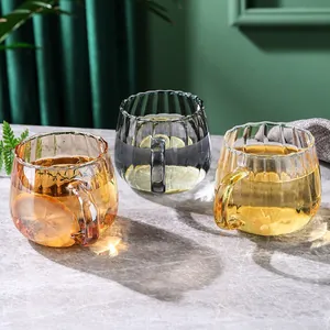 Drei farbige geriffelte Kaffeetassen aus Glas mit Henkeln in luxuriöser Umgebung