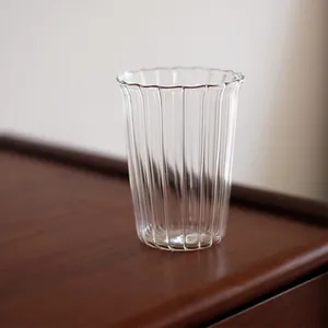 Élégante tasse en verre côtelé avec bord en forme de pétale sur table en bois sombre