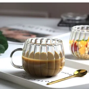 Nahaufnahme der gerippten Kaffeetasse aus Glas mit Griff und Latte Art beim Frühstück