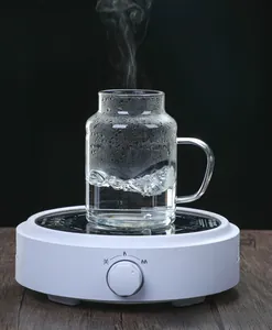 Macro shot of heat-resistant striped glass cup and teapot set on electric heating base