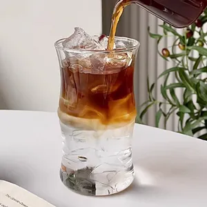 Minimalist bamboo-shaped borosilicate glass cup being filled with iced coffee drink