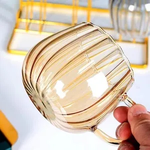 Eleganter bernsteinfarbener Kaffeebecher aus Glas mit Rillen und Griff in warmer Umgebung