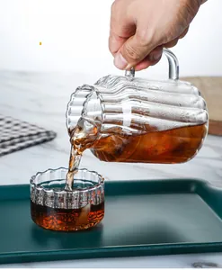 Macro shot of tea pouring into a heat-resistant striped glass set on a marble desk