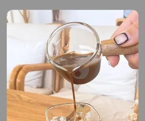 Detailed view of square glass coffee cup with wood handle pouring espresso smoothly