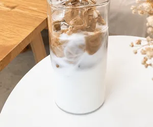 Detail of transparent square glass cup with matching dust cover on a wooden table