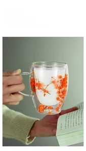 Detail of double-walled glass mug with embedded dried orange flowers and clear handle
