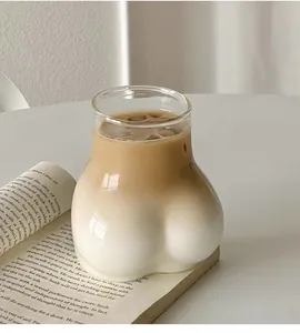Detailed view of butt-shaped glass filled with layered iced latte on a book background