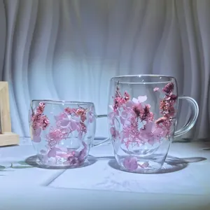 Elegant double-wall glass cups with pink dried flowers inside and clear glass handles