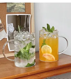 Detail of two large glass mugs with C-shaped handles and refreshing fruit tea drinks