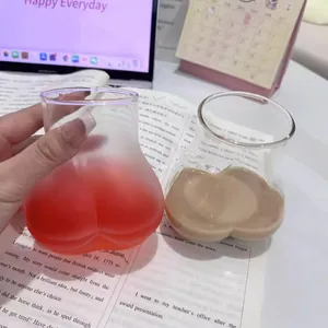 Detailed close-up of creative butt-shaped glass cups filled with colorful drinks on a desk.