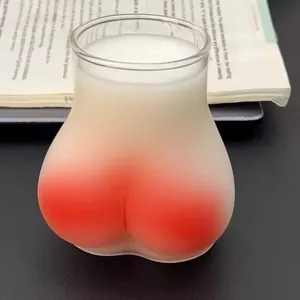 Close-up of a creative peach butt-shaped glass with frosted gradient and white liquid