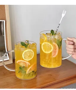 Close-up of a large glass mug with handle containing fruit tea, ice, and a metal stirrer
