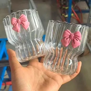 Close-up of heat-resistant glass coffee cup with vertical ribs and pink bow accent