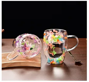 Nahaufnahme der doppelwandigen Glastasse mit bunten Trockenblumen und Holztablett