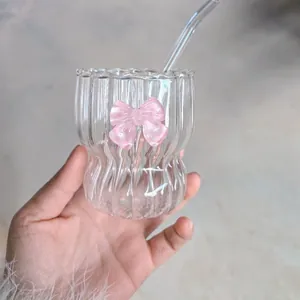 Close-up of ripple glass cup with pink glitter bow and glass straw for girls