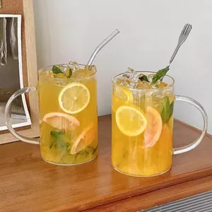 Two 1000ml glass cups with handles filled with iced fruit tea and lemon slices on a desk