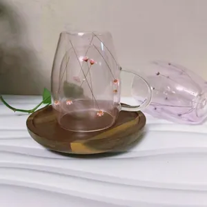 Detail of double-walled glass cup with pink dried flowers and solid wood saucer