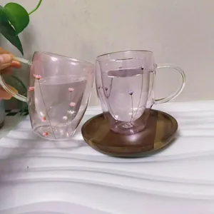 Close-up of heat-resistant double-walled glass cups with pink flowers and a wooden tray