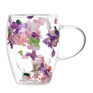 Doppelwandige Kaffeetasse aus Glas mit bunten getrockneten Blumen und klarem Handgriff