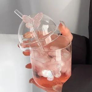 Elegante bicchiere in vetro con farfalle rosa e coperchio a cupola tenuto in mano con bevanda