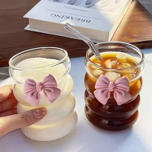 Detail of wavy glass cups with pink 3D bows and glass straw for cold drinks