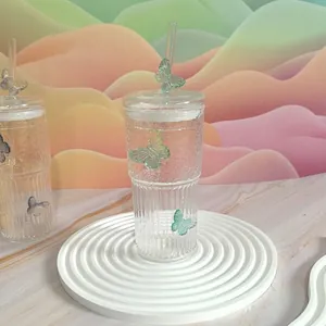 Detailed close-up of ribbed glass tumbler with green butterfly ornament and glass straw