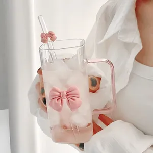 Gros plan d'une tasse carrée en verre avec nœud rose, poignée et paille