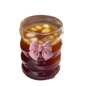 Aesthetic wavy glass coffee cup with pink bow and straw on white background