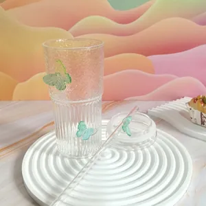Detail view of butterfly glass cup with textured body, glass lid and a matching straw