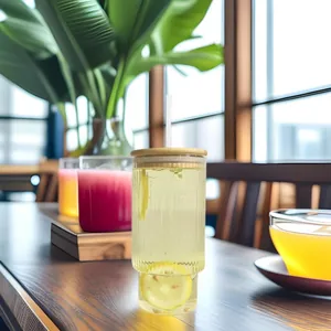 Detail of 700ml ribbed glass cup with a bamboo lid and a straw on a wooden table