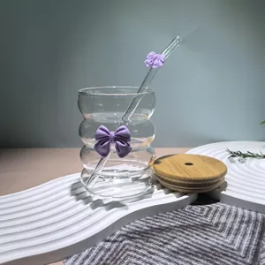 Detail of wavy glass cup with purple bow accent, glass straw, and natural bamboo lid