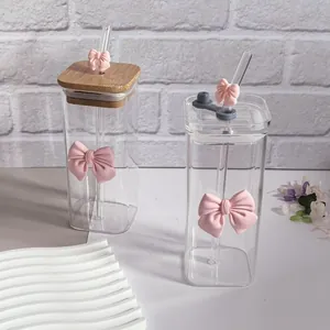 Detail of square glass cups with bamboo lids, glass straws and pink bow decorations