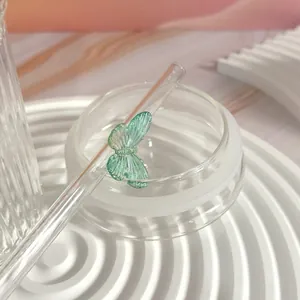 Detailed macro view of a glass straw featuring a delicate translucent green butterfly
