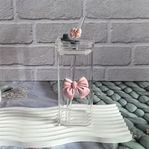 Square glass water bottle with pink 3D bows and matching straw on white pedestal