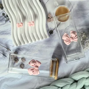 Close-up of square glass cup with pink bow decoration and matching glass straw