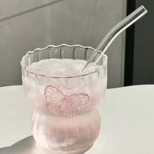 Macro view of clear glass coffee cup with pink butterfly detail and glass straw